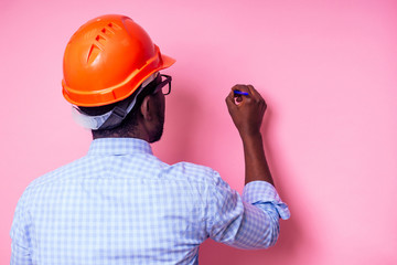 black man African American writing down ideas in a notebook paints the wall in pink color .happy...