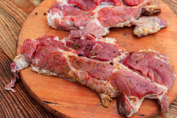 Fresh raw pork meat with spices on wooden cutting board on rustic table