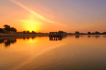 Amazing panoramic view of Gadisar or Gadi Sagar Lake with the view of historical building and temple during sunrise in Jaisalmer, India.