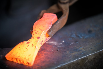 Blacksmith and anvil. Blacksmith working with red hot metal workpiece of new hammer on the anvil