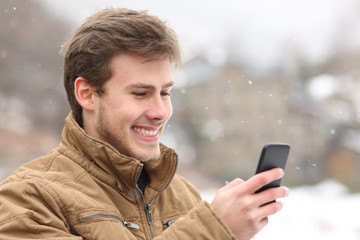 Happy man checking phone on winter holiday