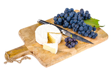 Camembert cheese with black grapes on wooden board