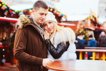 happy loving couple enjoying Christmas or New year Holidays outdoor, walking on city festive market with street food