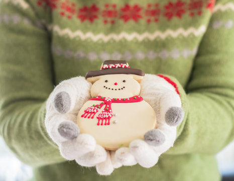Christmas cookie gingerbread snow man, winter homemade dessert snack in woman baker's hand in winter glove 