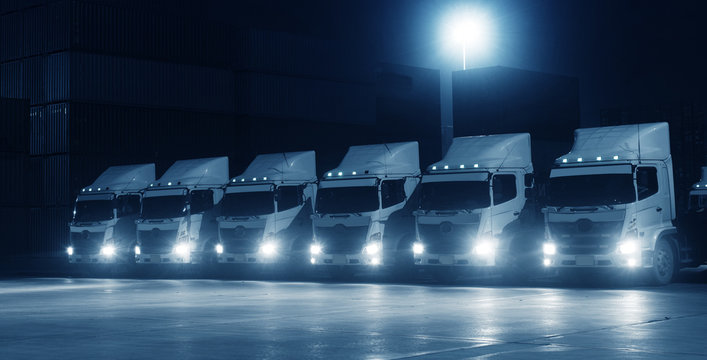 New truck fleet in the container depot at night in blue tone for transportation industry logistics background.