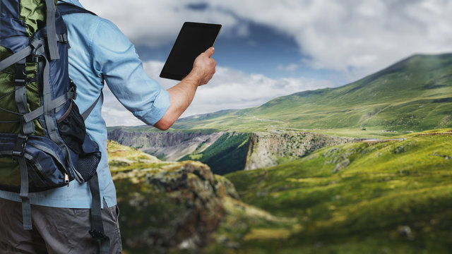 Young traveler hiker with backpack looking at the route map in a digital tablet. The concept of a modern adventure