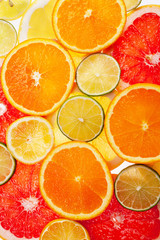 Background of different colored slices of citrus fruits close up.
