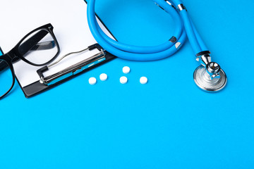 Stethoscope, clipboard and pills, closeup. Medical equipment