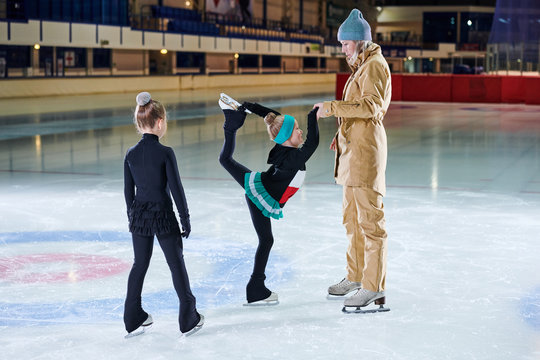 Side view portrait of little girl figure skating beautifully during training with female coach in indoor rink, copy space