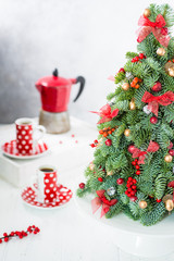 Christmas tree with cups, geyser coffee maker on a white table with copy space.