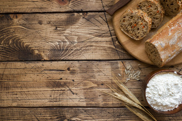 Fresh bread with sunflower seeds, sesame seeds and flax are cut into pieces on a cutting board. Wooden background, copy space