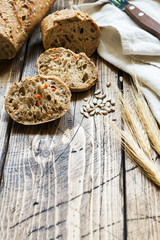 Fresh bread with sunflower seeds, sesame seeds and flax are cut into pieces on a cutting board. Wooden background, copy space