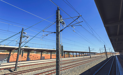 Train tracks with overhead catenary and electric lines in a blue sky morning