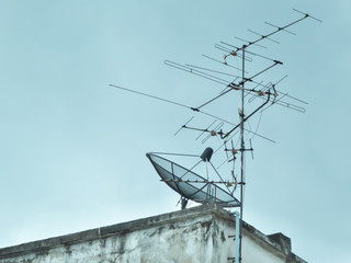 Home satellite dish and TV antenna on top of building, Bangkok, Thailand.