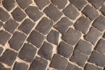 Natural abstract background. The texture of the old gray stone road. Cropped shot, close-up, nobody, horizontal. Concept of history and construction.