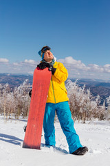 Young male snowboarder with snowboard on winter holiday in the mountain