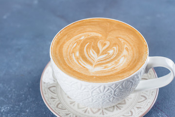 Сoffee cup on blue concrete table background. Latte or Cappuccino with frothy foam.