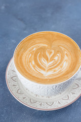 Сoffee cup on blue concrete table background. Latte or Cappuccino with frothy foam. Top view