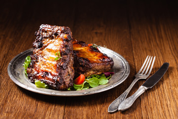 Roasted ribs, served on an old plate. Dark or balck background.