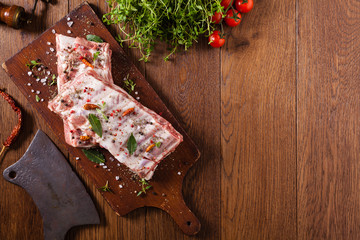 Raw pork ribs, on a plate sprinkled with spices.