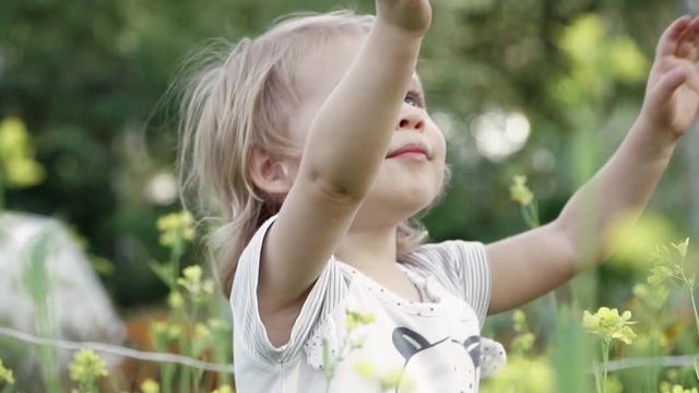Little girl in yellow flowers in meadow on summer day