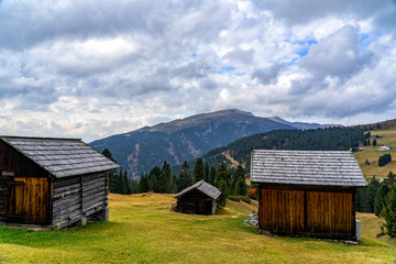 Obraz premium Wooden shed on a grassy meadow in a mountains.