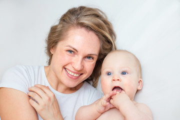 mother is playing with her baby son in the bedroom