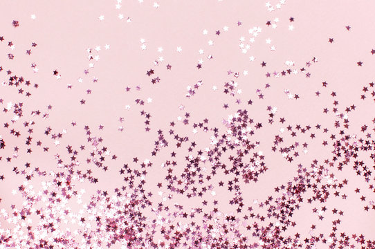 Pink holographic glitter confetti in the form of stars on pink background Flat lay top view copy space. Festive holiday pastel backdrop. Birthday, congratulations, Christmas, New Year