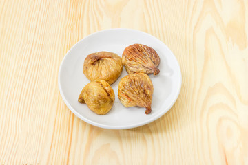 Dried figs on the white saucer on a wooden surface