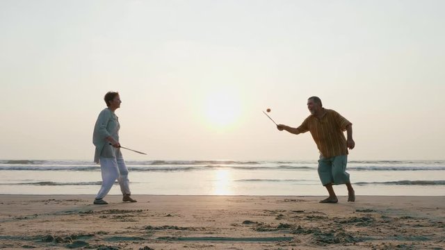 Active senior couple playing tai chi ballon ball at the beach in slow motion.