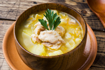 Fish soup in a wooden bowl with fresh herbs.
