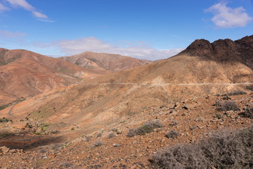 Fototapeta na wymiar Rocky hill landscape with road in Fuerteventura. Canary Islands, Spain