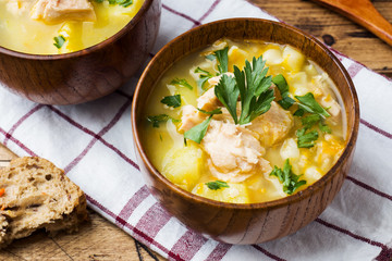 Fish soup in a wooden bowl with fresh herbs.
