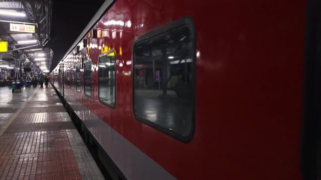 A still, point of view shot of a train leaving the station while people are rushing to get on.