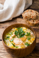 Fish soup in a wooden bowl with fresh herbs.