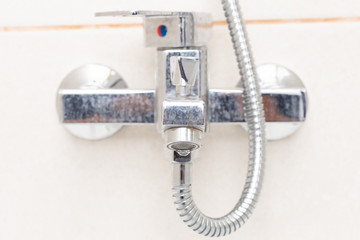 Drop leaking from shower tap close-up.