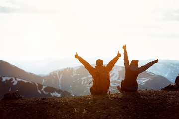 Two hikers on mountain top with raised arms