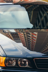 Concept of car in real world. Front of automobile close up. Blue sky reflected in metallic body and...