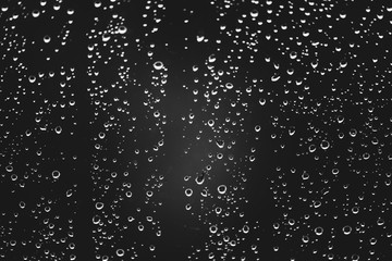 Obraz premium Dirty window glass with drops of rain. Atmospheric monochrome dark background with raindrops. Droplets and stains close up. Detailed transparent texture in macro with copy space. Rainy weather.