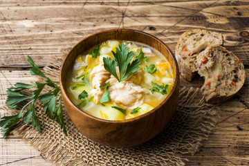 Fish soup in a wooden bowl with fresh herbs.