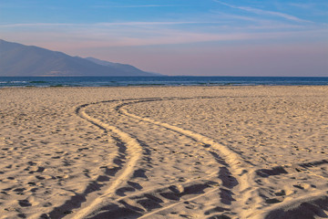 Fototapeta na wymiar Traces in the sand. Morning landscape on the beach of Keramoti, Aegean Sea, Greece.