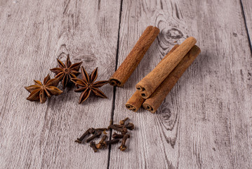 Cinnamon sticks with anise stars and cloves on wooden table.