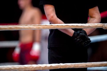 Boxing ring ropes and referee in black clothes in ring two fighters MMA, boxing martial arts...