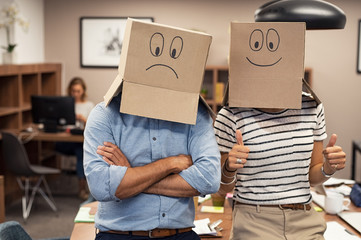 Positive businesswoman and negative man covering face with cardboard