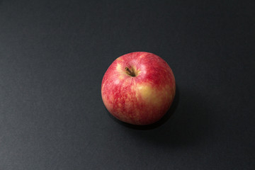 Fototapeta na wymiar Whole red ripe apple with tail against black background