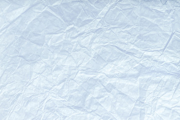 Texture of crumpled light blue wrapping paper, closeup. White old background.