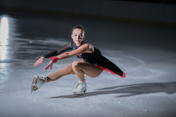 A beautiful ice skater is preparing to start her performance on the ice.