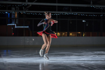A beautiful ice skater during her performance on the ice. She is wearing a gorgeous costume.
