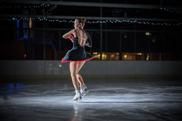 An ice skater is spinning on the ice during her performance. She looks gorgeous and her performance is magnificent.