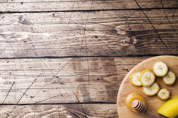 Banana and sliced banana into pieces with honey on wooden background, copy space.
